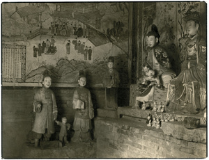 Statues and murals in a temple dedicated to childbirth, with small thanksgiving gifts from mothers