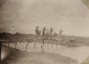 Dr James Laidlaw Maxwell and porters crossing a wooden foot bridge near Donggang, Taiwan