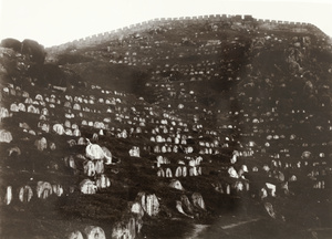 A graveyard on a slope by city walls