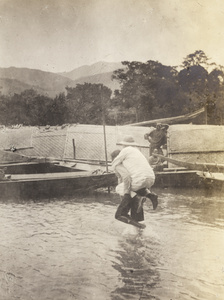 A missionary being carried over water to a boat