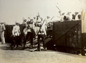 British soldiers and a gun on a train at a railway station