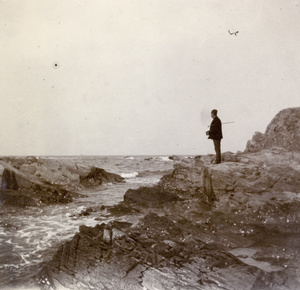 Man with a camera, on rocky coastal outcrop, Weihaiwei