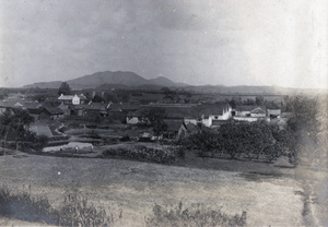 Farm buildings and houses by a city wall