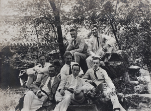 Seven men, including Hulme, posed on garden rocks