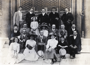 Group posed on steps, including a woman with a camera