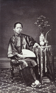 Portrait of a woman, with a fan, vase of flowers and a pipe