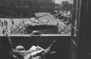 Soldier reading on balcony above guard post, Shanghai