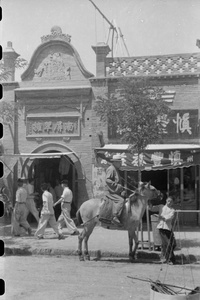 Man astride horse outside shop