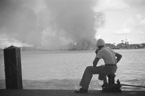 Sikh man looking over Huangpu River towards fires in Pudong, Shanghai