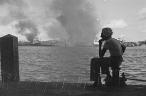 Sikh man looking over the river towards fires in Pudong, Shanghai