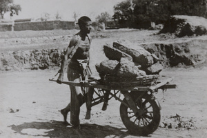 Worker moving rocks with wheel barrow