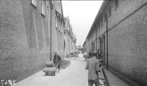 Porters in alleyway between godowns and sheds, Canton