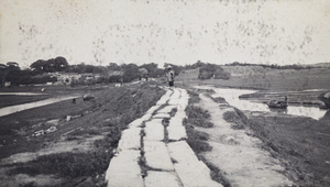 A stone-paved road, a stream, fields and a village