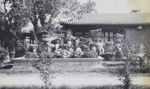 People posed among ornamental rocks, by a flower bed in a garden